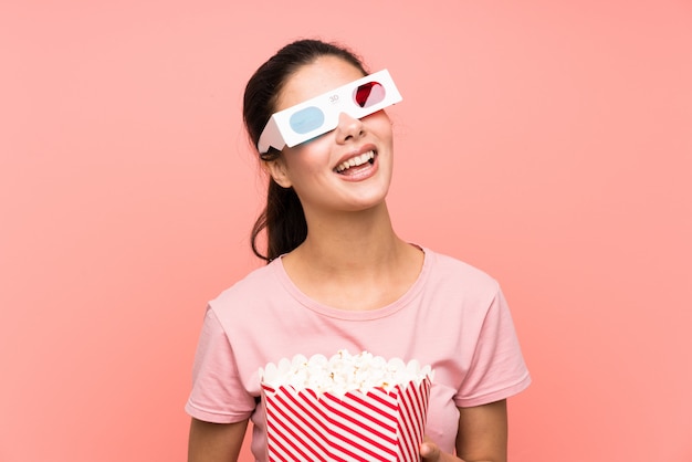 Fille adolescente sur mur rose isolé, manger des pop-corn avec des lunettes 3d