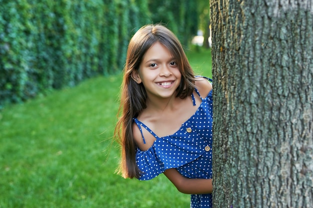 fille adolescente près d'un arbre dans un parc d'été au coucher du soleil