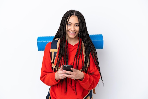 Fille adolescente de randonneur avec des tresses sur fond blanc isolé envoyant un message avec le mobile