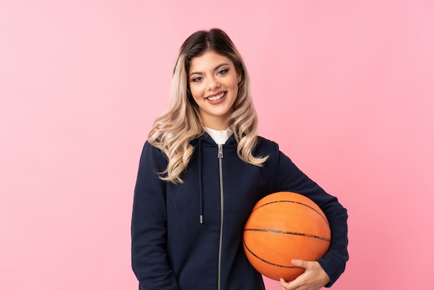 Fille adolescente sur rose isolé avec ballon de basket