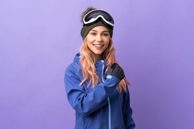 Fille adolescente skieur avec des lunettes de snowboard sur mur violet isolé célébrant une victoire