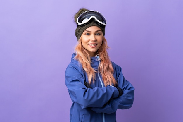 Fille adolescente skieur avec des lunettes de snowboard sur violet isolé avec les bras croisés et impatient