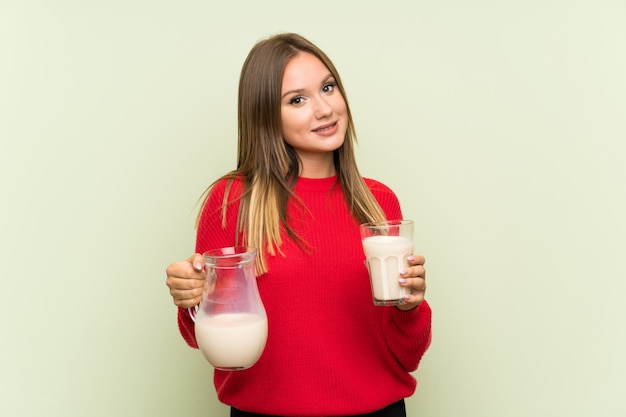 Fille adolescente tenant un verre de lait sur fond vert isolé