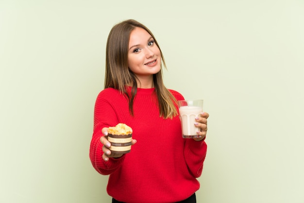 Fille adolescente tenant un verre de lait et un muffin