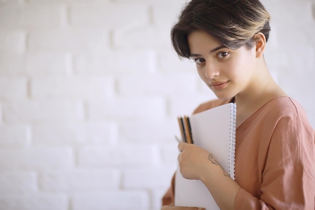 une fille adulte dessine sur des crayons de papier / portrait d'une belle jeune étudiante, éducation à l'école d'art, concept d'éducation artistique