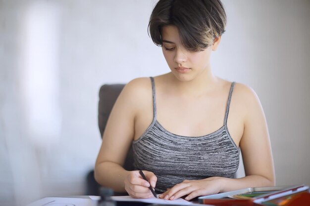 une fille adulte dessine sur des crayons de papier / portrait d'une belle jeune étudiante, éducation à l'école d'art, concept d'éducation artistique