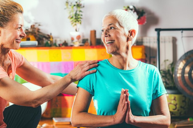 Photo une fille adulte qui aide sa mère à pratiquer le yoga au spa.