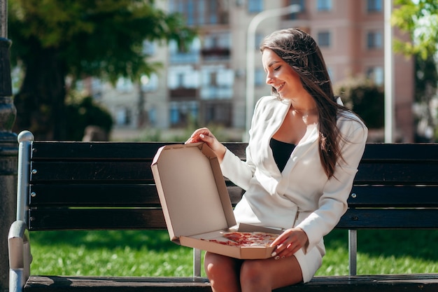 Fille d'affaires souriante, manger de la pizza dans la rue