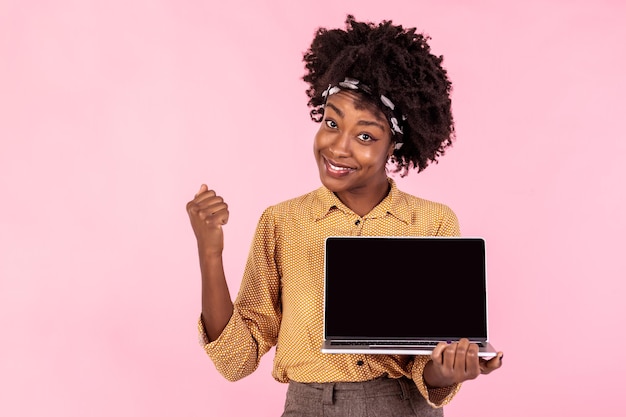 Une fille africaine excitée tenant un ordinateur portable à écran noir Une femme d'affaires heureuse pointant sur l'écran de l'ordinateur portable Concept publicitaire