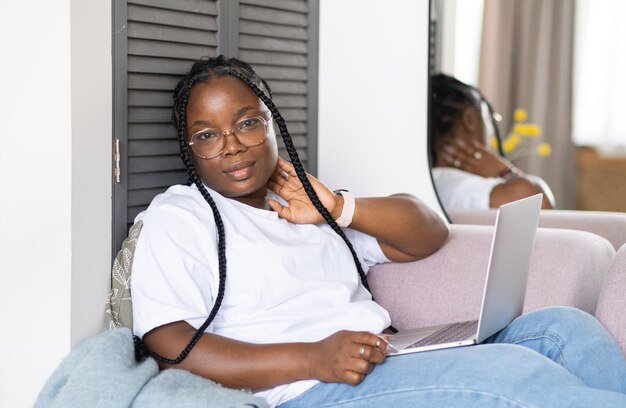 Fille africaine heureuse et attrayante travaillant au bureau à distance depuis chez elle Femme noire utilisant un ordinateur portable Apprentissage à distance Enseignement en ligne et travail