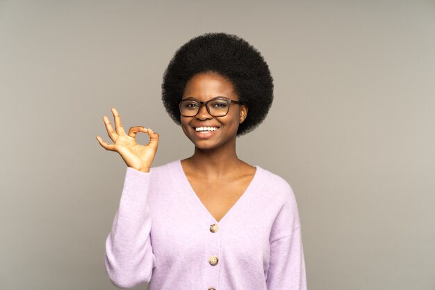 Une fille africaine heureuse montre un geste correct donner de bons conseils ou aider un client satisfait d'une entreprise ou d'un service