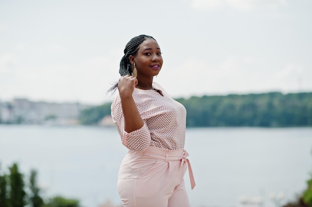 Une fille africaine posée dans la rue de la ville porte un chemisier et un pantalon pêche