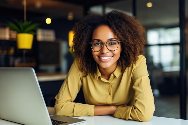 une fille africaine souriante avec des lunettes assise à un bureau pour le travail