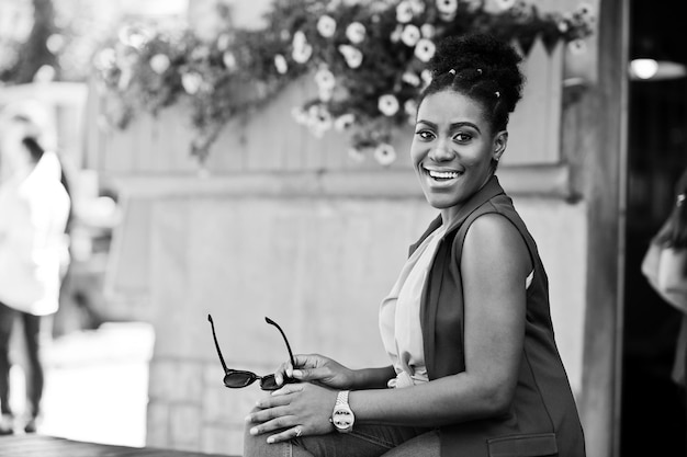 Fille afro-américaine assise en plein air avec des lunettes de soleil à la main