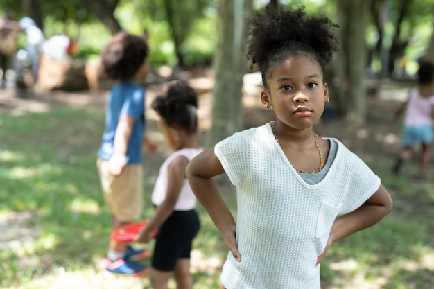 Fille afro-américaine aux cheveux bouclés avec des amis jouant ensemble dans le parc