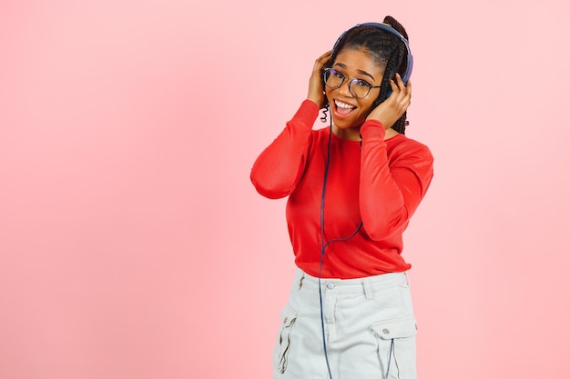 Fille afro-américaine dans les écouteurs sur fond rose