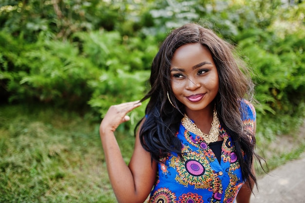 Photo fille afro-américaine dans des vêtements colorés assis en plein air