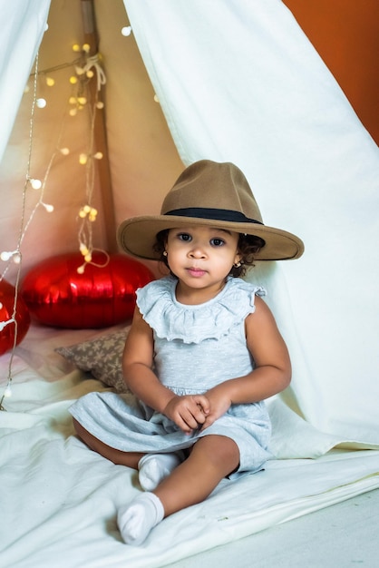 Fille afro-américaine noire jouer dans une tente wigwam enfant dans un chapeau rire s'amuser enfance heureuse