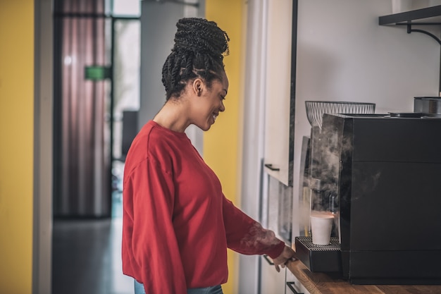 Fille afro-américaine de profil près de la machine à café