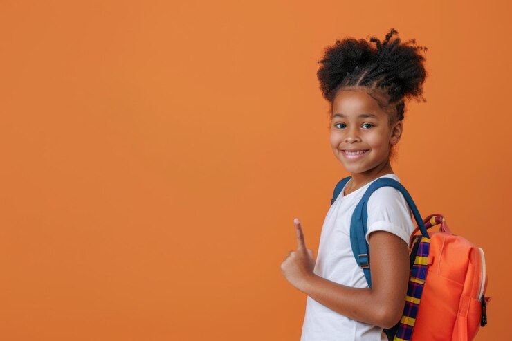 Une fille afro-américaine souriante avec une coiffure afro pointant vers le haut portant une chemise blanche et un sac à dos orange sur un fond orange
