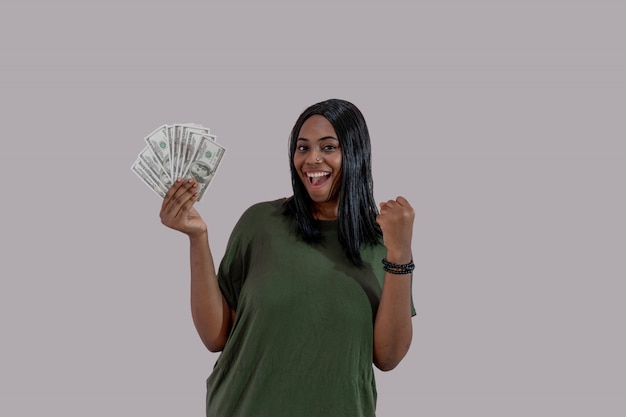 Fille afro-américaine tenant beaucoup de billets en argent et souriant