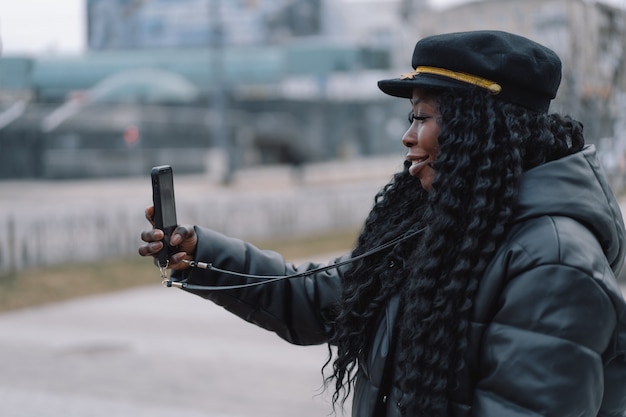 Une fille afro utilise le téléphone à l'extérieur en utilisant la technologie