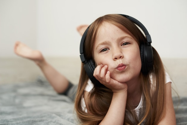 Une fille d'âge préscolaire écoute de la musique sur son lit