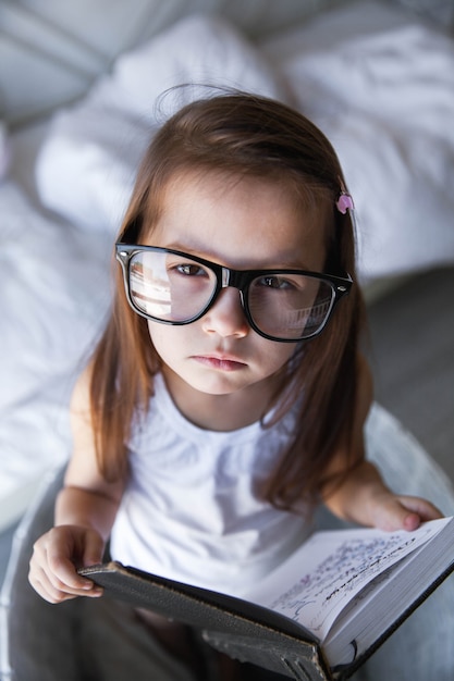 Fille d'âge préscolaire avec des livres et des lunettes. enseignement, étudiant, éducation