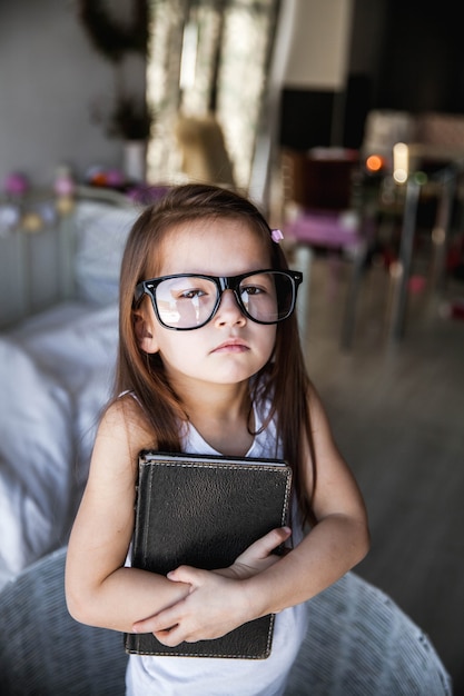 Fille d'âge préscolaire avec des livres et des lunettes. enseignement, étudiant, éducation