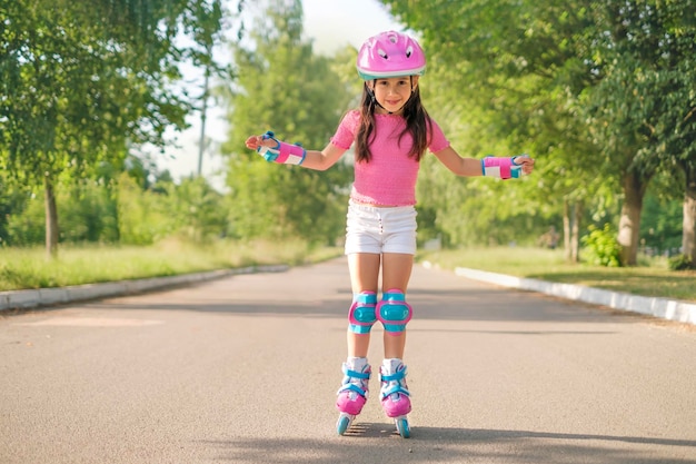 Une Fille D'âge Préscolaire Portant Un Casque De Protection Et Des Patins à  Roulettes Roule Sur Un Chemin D'asphalte