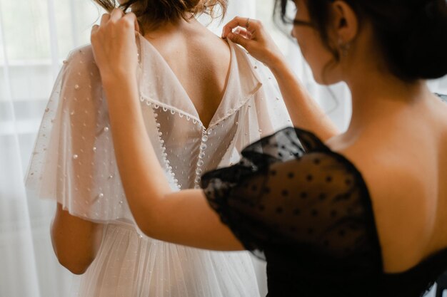 Fille aidant la mariée à mettre sa robe de mariée