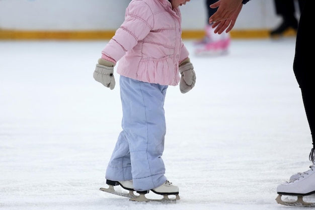 La fille aide l'enfant à patiner