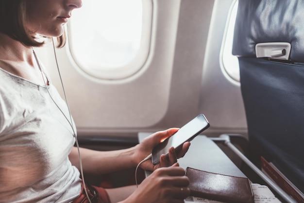 Fille à l'aide d'un smartphone en volant dans un avion