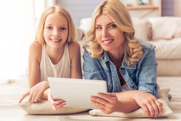 Fille à l'aide d'une tablette, regardant la caméra et souriant.