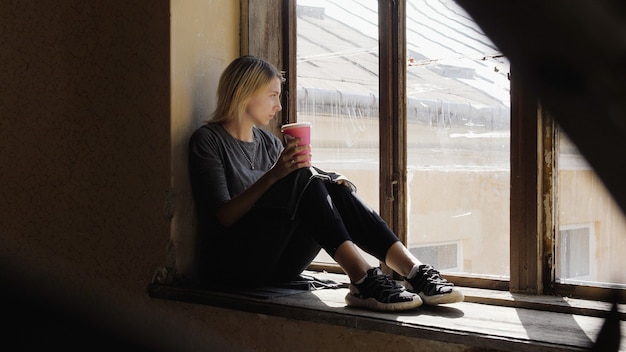 La fille a l'air très triste, à la fenêtre se trouve sur un escalier