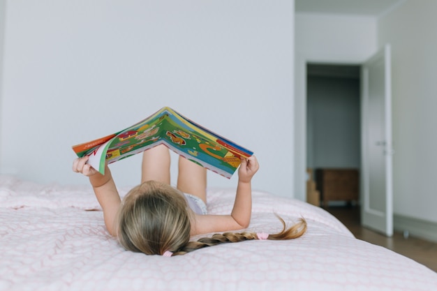 Fille allongée sur le lit et livre de lecture