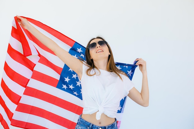 Fille américaine Heureuse jeune femme en lunettes de soleil en forme de coeur sur le drapeau américain sur fond blanc