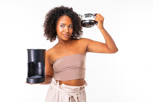 Fille américaine avec une tasse de café et une machine à café sur un mur blanc