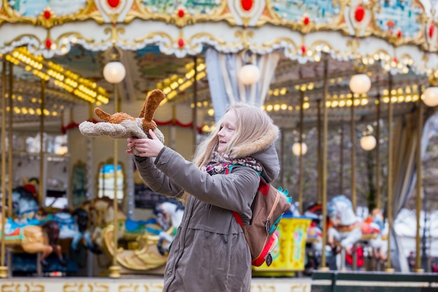 Photo fille amusante avec un chien jouet sur le fond du carrousel français. paris, france