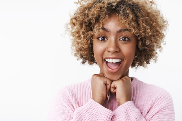 Fille amusée attendant excitée pour un voyage de vacances se sentant ravie d'anticiper avec joie et bonheur souriant largement et enthousiaste se tenant la main sous le menton en regardant la caméra hypnotisée