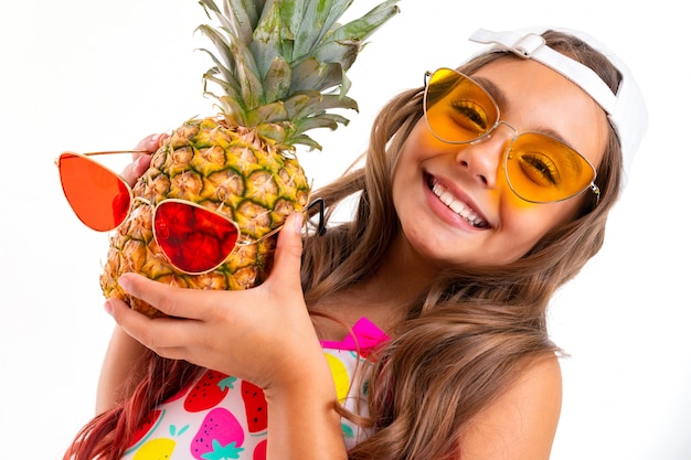 Fille avec ananas et lunettes rétro sur un mur blanc