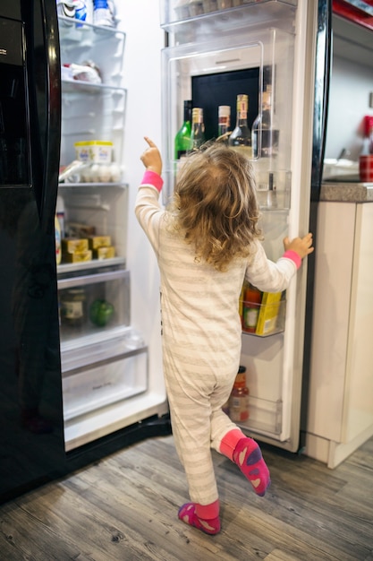 Fille anonyme en choisissant la nourriture du réfrigérateur