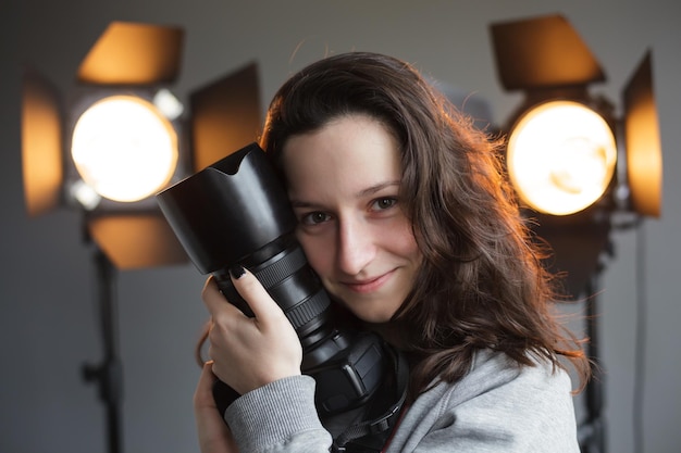 Fille avec un appareil photo dans le studio sur le photographe hipster d'éclairage de fond