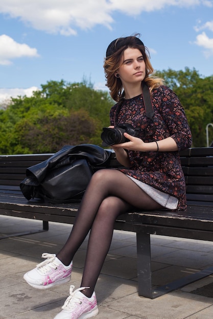 Fille avec l'appareil photo numérique assis sur un banc