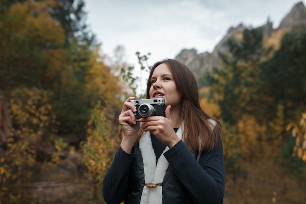 Fille avec appareil photo rétro dans les montagnes d'automne