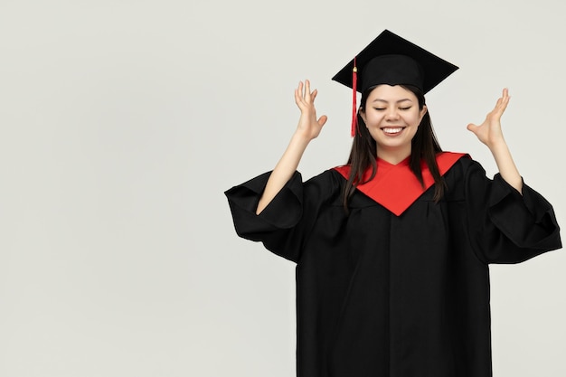 Une fille d'apparence asiatique diplômée d'un collège sur un fond gris