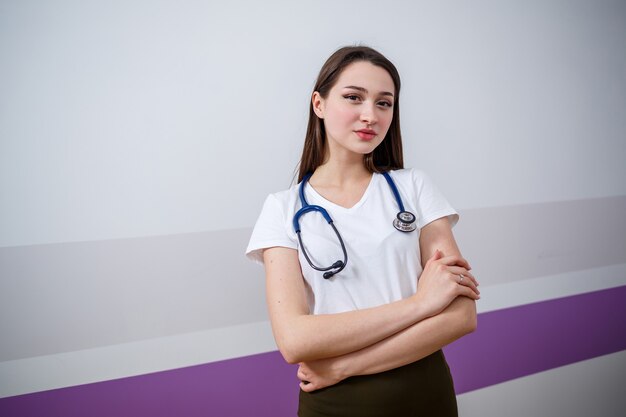 Une fille d'apparence européenne avec un phonendoscope sur le cou. Sourires de jolie jeune femme brune. C'est une jeune médecin, étudiante interne