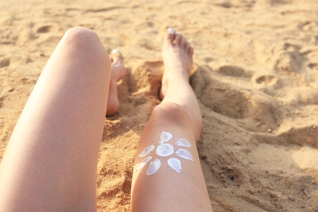 Fille appliquant un écran solaire sur ses jambes Soins de la peau Corps Protection solaire