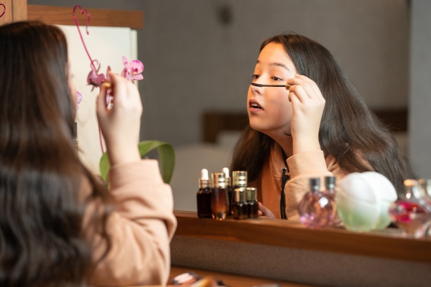 Fille applique le maquillage assis devant le miroir.