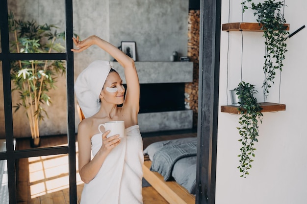 Une fille applique des patchs oculaires anti-âge et sourit le matin du week-end à la maison ou dans une station thermale luxueuse